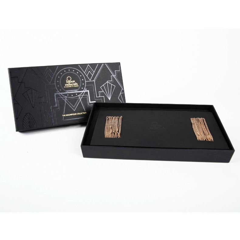 Coffret noir ouvert The Magnifique Collection Bijoux Indiscrets revelant la chaine de corps doree pliee sur le velours, packaging premium sur fond blanc