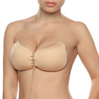 Soutien-gorge adhesif Lace-it beige porte de face sur buste nu, coupelles push-up a lacage avant resserrant la poitrine pour un effet decollete galbe et rehausse.