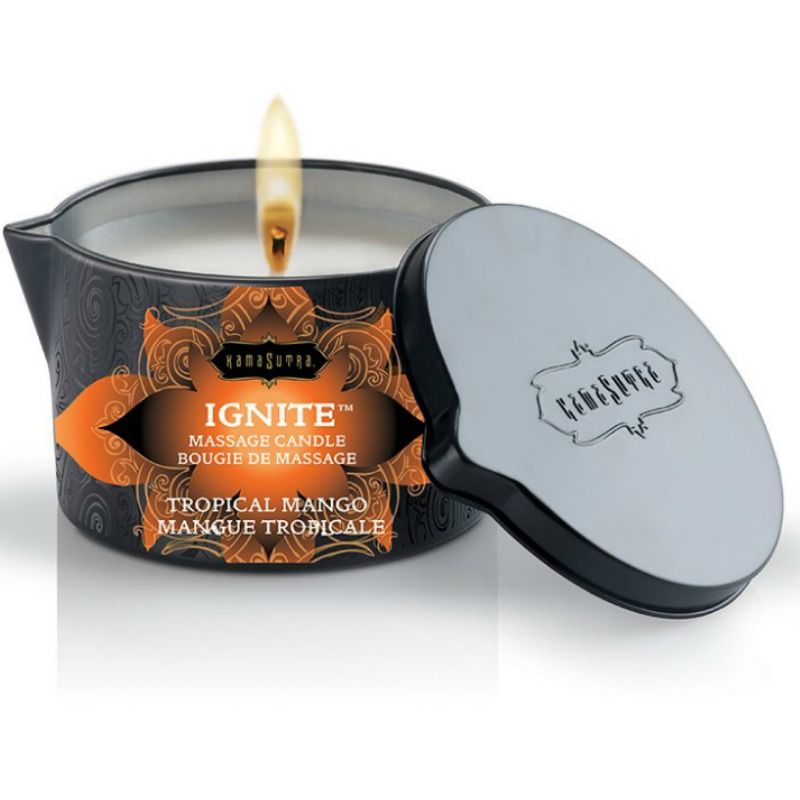 Bougie de massage Kamasutra Ignite mangue tropicale allumee, couvercle metallique pose contre le pot, 170 g de cire fondant en huile de massage tiede, cuillere fournie.