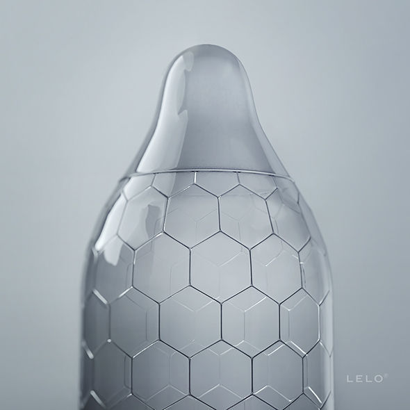 Gros plan sur l'embout reservoir d'un preservatif Lelo Hex transparent, latex a structure hexagonale sur fond gris, photo produit sans corps.