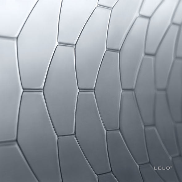 Macro de la texture hexagonale du preservatif Lelo Hex, alveoles de latex transparent en relief sur fond gris, visuel materiau sans anatomie.