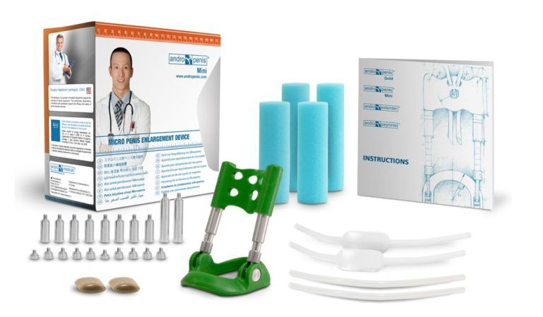 Contenu complet du kit Andropenis Mini vert pose a plat avec boite, supports en mousse, vis de reglage, bandes silicone et notice illustree du dispositif de traction medicale