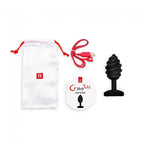 Accessoires du plug anal G-Vibe : pochette de rangement satinee blanche, cable de charge USB rouge et guide utilisateur rond illustrant le plug torsade noir.