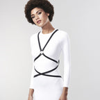 Modele en robe blanche portant le harnais multi-voies Bijoux Indiscrets, sangles noires a anneau dore croisees sur le buste, look bondage chic ajustable vegan.