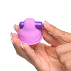 Gros plan sur un suceur de téton Suck-Her tenu entre les doigts, moteur vibrant violet foncé visible