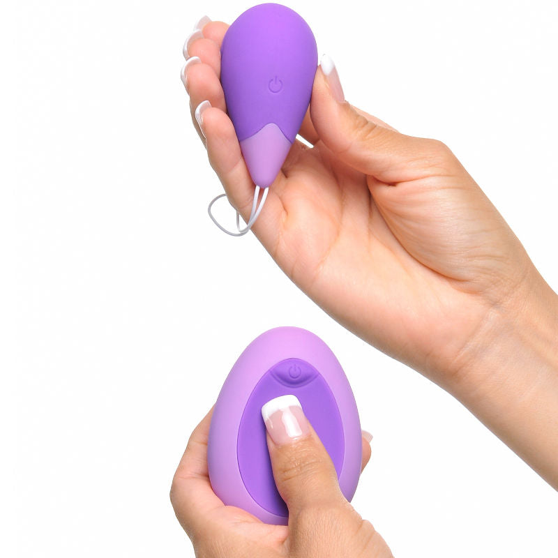 Boule kegel et télécommande Excite-Her tenues en main, doigt appuyant sur le bouton de la télécommande