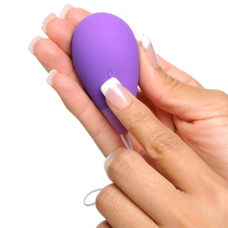 Boule kegel violette nichée dans la main, pouce sur le bouton marche/arrêt, cordon de retrait visible