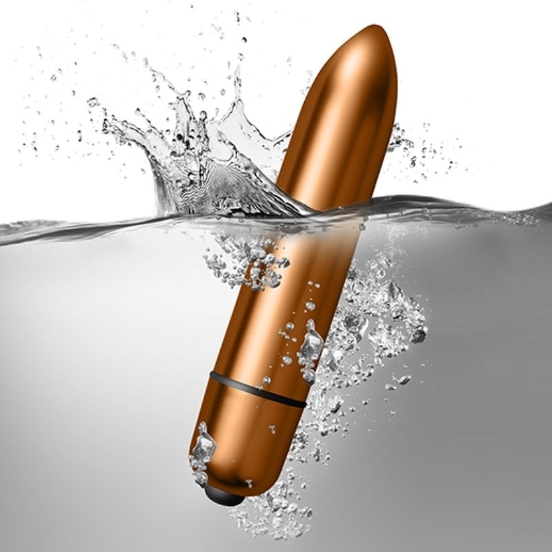 Balle vibrante cuivrée plongeant dans l'eau avec éclaboussures, illustrant l'étanchéité du mini vibromasseur du coffret Silhouette, surface métallisée lisse.