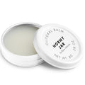 Baume clitoridien Horny Jar Bijoux Indiscrets, pot blanc ouvert laissant voir la texture cremeuse, couvercle pose a cote, cosmetique stimulant 8 g sur fond blanc