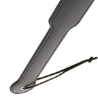 Gros plan de la base du paddle cuir noir Darkness avec oeillet metal et cordon de serrage, coutures laterales pour le jeu de domination BDSM