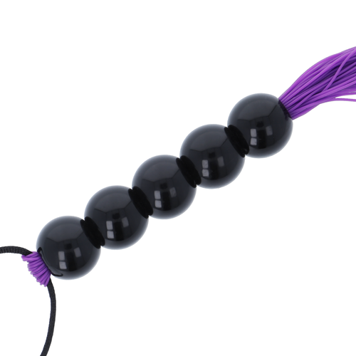 Gros plan sur le manche a perles noires lisses du fouet de bondage Darkness, billes brillantes alignees offrant une prise ferme et ergonomique en main.