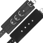 Manchette en cuir noir Darkness deployee montrant ses anneaux en D et sa sangle perforee a boutons-pression, accessoire de bondage poignets reglable.