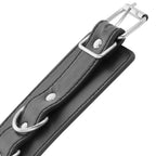 Gros plan sur la boucle metallique et l'anneau en D d'une menotte de cheville Darkness en cuir PVC noir, finition soignee pour la restriction des chevilles.
