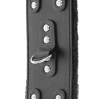 Gros plan sur l'anneau en D et les rivets d'une large menotte Darkness en cuir noir bordee de fausse fourrure, surpiqures visibles pour le bondage confortable.