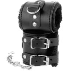 Paire de larges menottes Darkness en cuir PVC noir doublees de fausse fourrure, double boucle reglable et chaine a mousqueton pour une restriction douce des poignets.