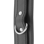 Detail de l'anneau en D argente et du rivet sur la sangle de cuir noir d'une menotte Darkness, finition soignee pour relier les poignets en bondage.