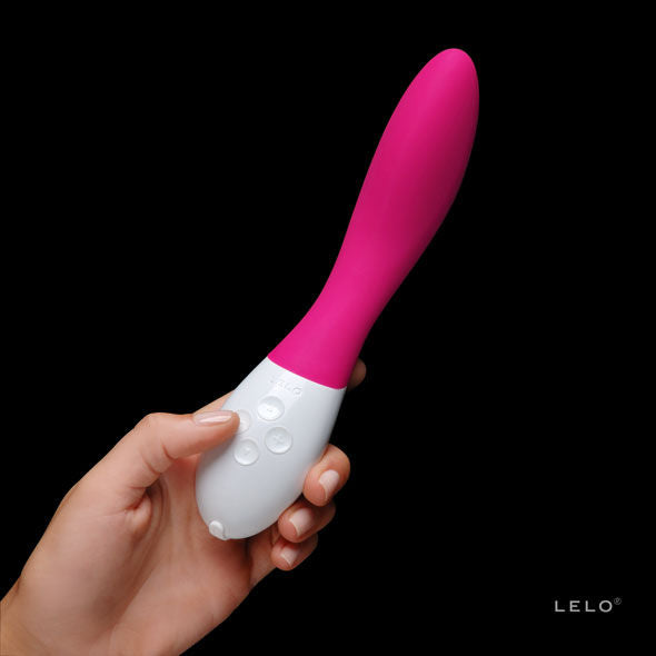 Masseur point G Mona 2 rose tenu en main sur fond noir, gros plan sur la poignee blanche a boutons, vibromasseur Lelo en silicone aux courbes ergonomiques.