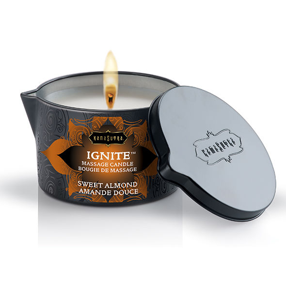 Bougie de massage Kamasutra Ignite amande douce allumee, couvercle gris pose contre le pot, cire enrichie au beurre de karite qui se transforme en huile de massage tiede.