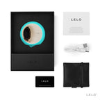 Coffret Lelo Ora 3 turquoise ouvert avec notice, cable de charge, carte de garantie et pochette noire, simulateur de plaisir oral a disque rotatif dore en silicone doux.