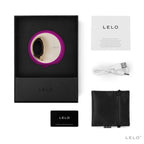 Coffret Lelo Ora 3 fuchsia ouvert avec notice, cable de charge, carte de garantie et pochette noire, simulateur de plaisir oral a disque rotatif dore en silicone doux.