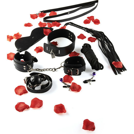 Kit BDSM complet Toy Joy etale sur petales de rose : fouet, collier, menottes et pinces a tetons noirs, vue d'ensemble du coffret 6 accessoires