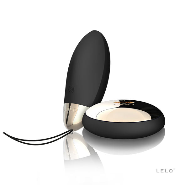 Œuf vibrant Lyla 2 de Lelo noir dressé derrière sa télécommande dorée posée à plat, embout chromé et cordon de retrait, set de stimulation interne discret.