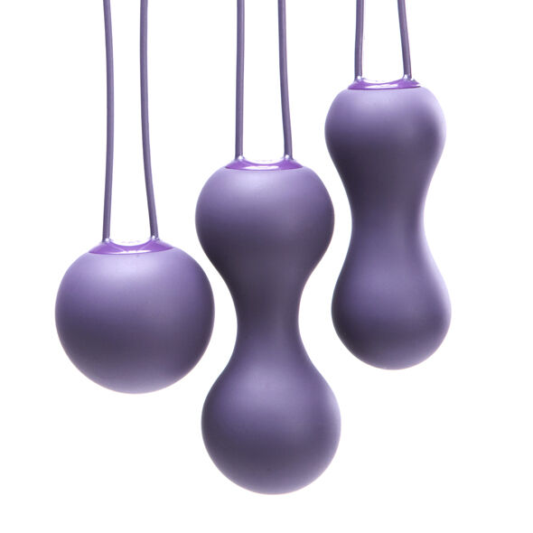 Gros plan sur les boules de Kegel Ami violettes suspendues par leurs cordons fins, billes simples et doubles en silicone mat détaillées de près sur fond blanc parfaitement épuré.