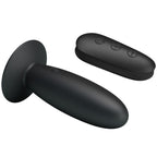 Plug anal Mr Play en silicone noir lisse couche sur sa base ventouse pres de la telecommande, embout arrondi, 12 modes de vibration sans fil etanches rechargeables USB.