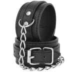 Paire de menottes en cuir texture noir Darkness, vue rapprochee sur la boucle metal argentee et la chaine de liaison, accessoire de restriction reglable pour les poignets.