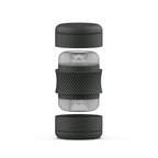 Masturbateur Bhandy éclaté en hauteur : capuchon noir, corps translucide central et fond noir séparés. Vue technique du cylindre démonté, surfaces neutres non anatomiques.