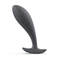 Plug prostatique fin anthracite à tête effilée et col mince, base plate évasée stabilisante. Profil élancé en silicone lisse posé sur fond blanc, contour épuré sans anatomie.