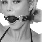 Gros plan en noir et blanc du baillon boule respirant porte, boule percee de trous et sangle en cuir a anneaux ajustee autour du visage.