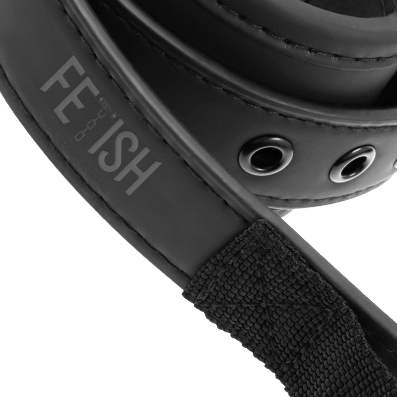 Gros plan sur la manchette en neoprene noir de la sangle doggy Fetish Submissive avec oeillets metal, logo grave et sangle textile pour ajuster le maintien des poignets.