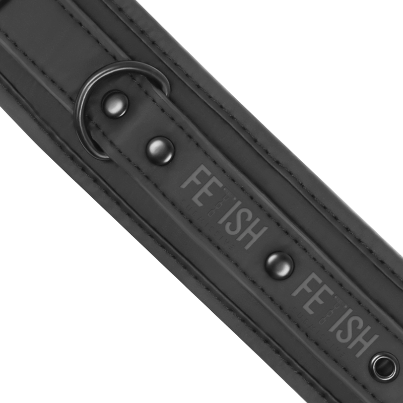 Detail de la sangle cuir vegan a anneau en D, rivets et logo grave du set collier menottes Fetish Submissive, neoprene noir mat