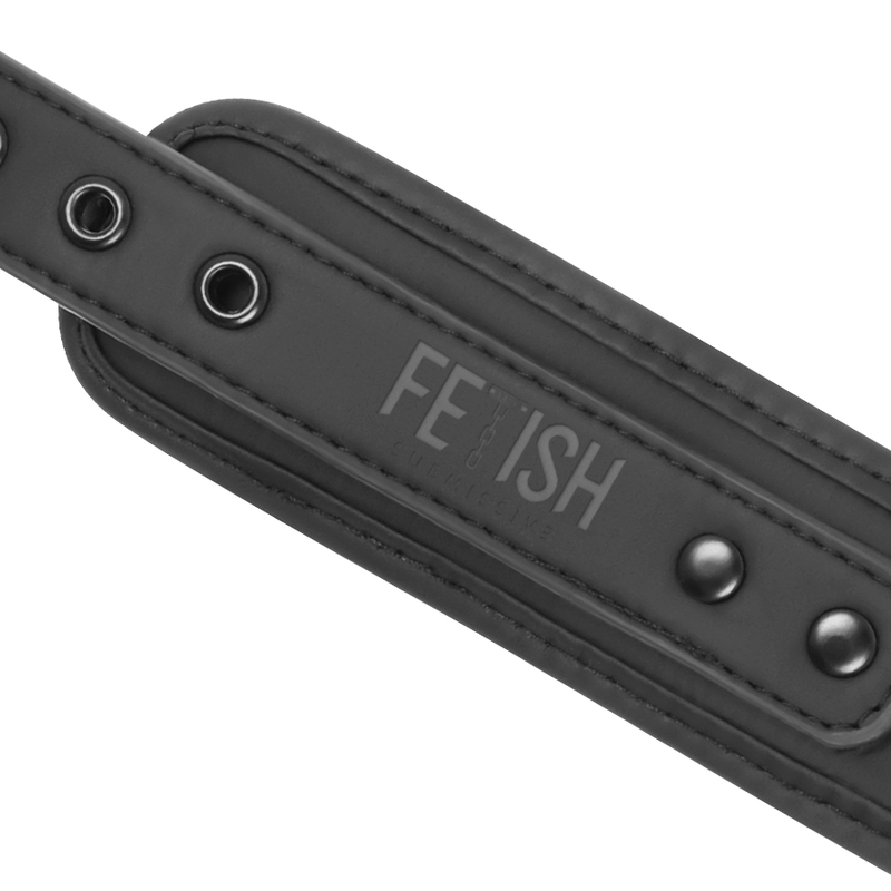 Detail macro d'une sangle cuir vegan a logo grave et rivets metal du set collier menottes Fetish Submissive, neoprene noir reglable